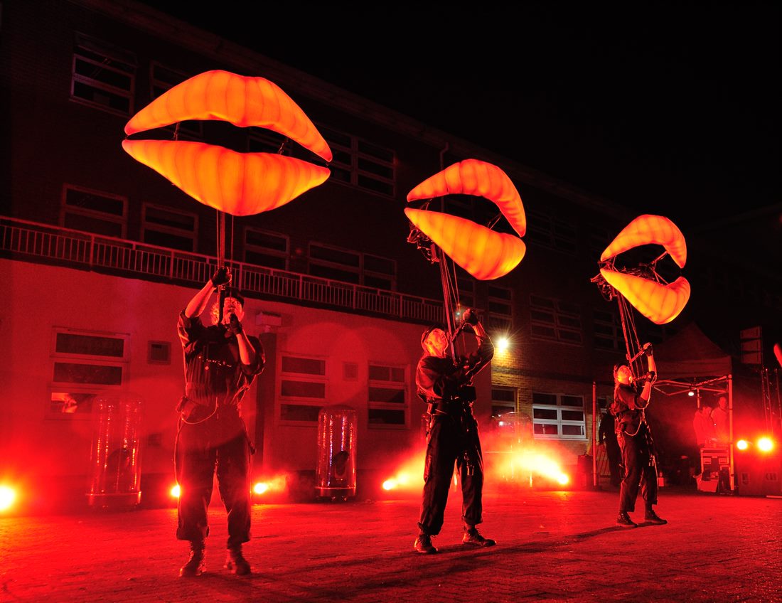 people holding large puppets in the shape of lips